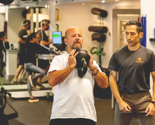 Coach guiding athlete through kettlebell lift during personal training at Sherpa in Westport, CT