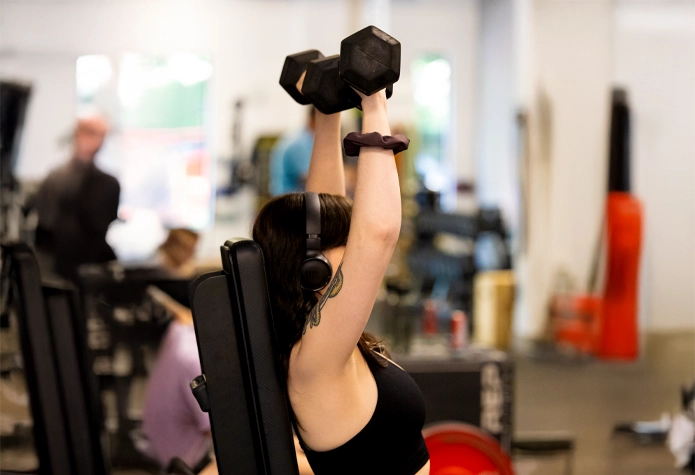 Woman lifting dumbbells during personal training workout at Sherpa in Westport CT