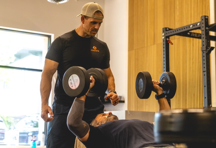 Sherpa trainer in Westport CT supervising client lifting dumbbells with proper form during personal training session
