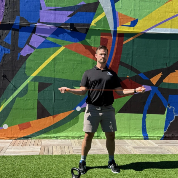 Luke Yoder demonstrates a golf swing rotation drill with resistance bands during a rooftop golf fitness workout in Westport, CT.