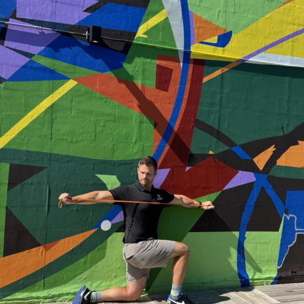 Luke Yoder coaches golfers through a resistance band exercise to improve core stability and balance for a stronger golf swing.