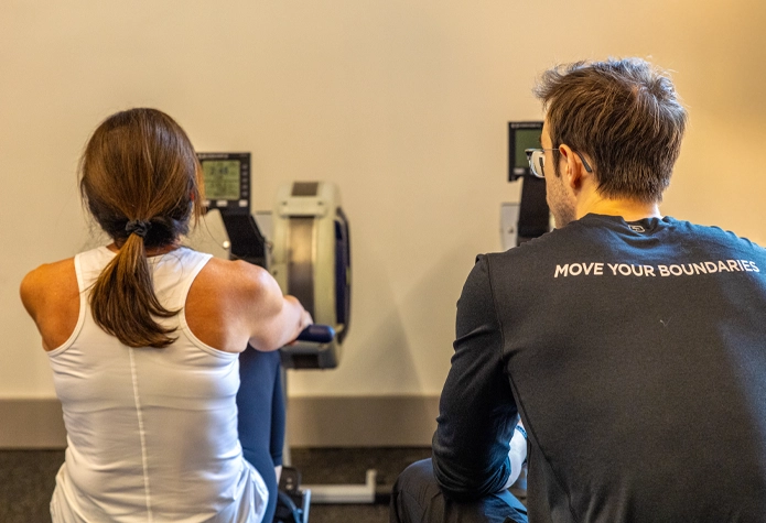 Sherpa coach watches form as a woman rows during functional strength training in Westport, CT.