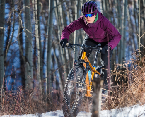 Woman fat biking in the snow on a forest trail during winter training