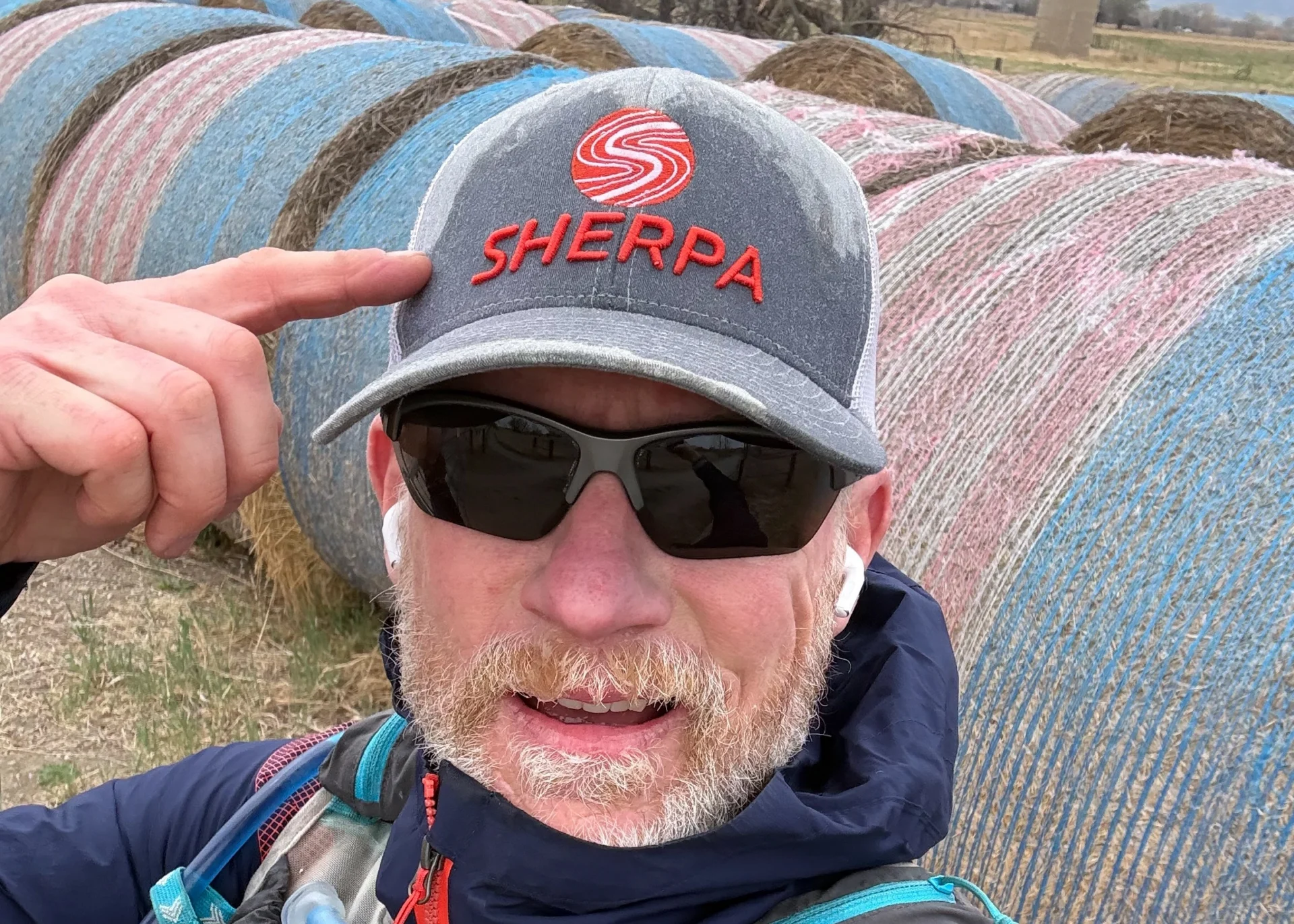 Andy Pemberton pointing at a Sherpa branded hat for a blog about Everest training and goal-specific fitness preparation