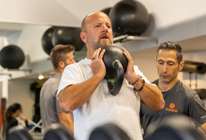 Sherpa Fitness coach guiding an older adult through kettlebell strength training in Westport, CT